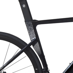 Close-up of a black bicycle frame and part of the wheel against a clean white background.