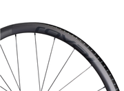 A close-up of the Roval Alpinist CLX II carbon wheelset shows its slim metal spokes and subtle branding on the tubeless-ready rim, set against a white background.
