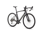 A matte black Roubaix SL8 Sport 105 12 Spd endurance road bike with drop handlebars, disc brakes, and thin tires is shown on a white background. The frame features "Specialized" in large white letters and includes Future Shock 3.0.