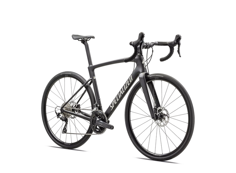 A matte black Roubaix SL8 Sport 105 12 Spd endurance road bike with drop handlebars, disc brakes, and thin tires is shown on a white background. The frame features "Specialized" in large white letters and includes Future Shock 3.0.