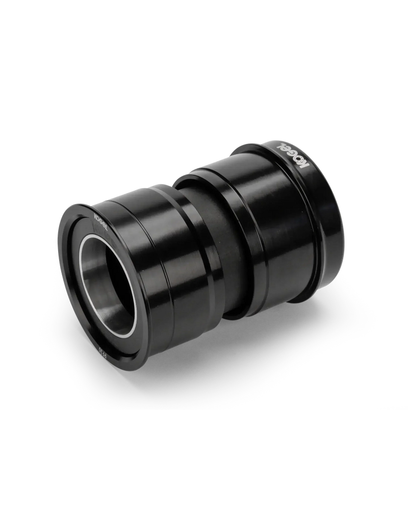 The Kogel Ceramic Bottom Bracket BBR-DUB is a black, cylindrical bottom bracket with smooth, shiny metal surfaces and visible ball bearing rings, perfect for upgrading your SRAM DUB crankset road bike. Shown against a white background.