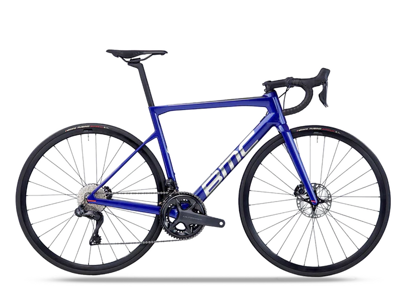 A sleek blue BMC Teammachine SLR Five SHIMANO 105 Di2 road bike with a carbon frame, drop handlebars, thin tires, and disc brakes, shown from the side on a white background.